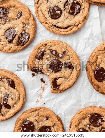 The picture you sent me shows a group of freshly baked chocolate chip cookies with melting chocolate and a sprinkle of salt, laid out on a sheet of parchment paper. It is a classic American recipe. 