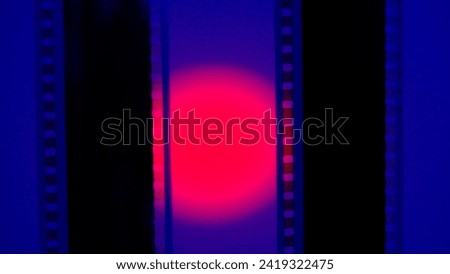 Two vertical film strips on a blue background with red circular light, close up. 35mm film slide frame. Long, retro film strip frame. Copy space. Royalty-Free Stock Photo #2419322475