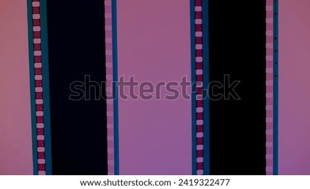 Two vertical film strips on a pink background, close up. 35mm film slide frame. Long, retro film strip frame. Copy space. Royalty-Free Stock Photo #2419322477