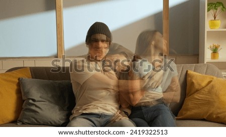 Portrait of man and girl in the room on the couch. Woman starts scream in tension shouts expressively, man is calm, both hugging at same time. Double exposure. Royalty-Free Stock Photo #2419322513
