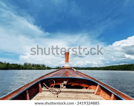 Ship Nose Front View Long tail boat at Thailand. A traditional long tail boat with decoration flowers and ribbons cruising. White cloud and clear sky. Royalty-Free Stock Photo #2419324885