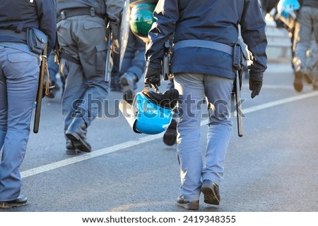 many policemen in uniform with riot gear during the protest demonstration with helmets and shields Royalty-Free Stock Photo #2419348355