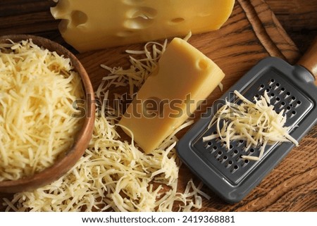 Grated, cut cheese and grater on wooden board, above view