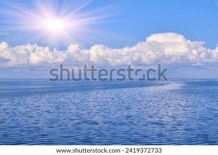 A tranquil seascape with gentle ripples on the water and billowy white clouds in the sky, their reflections dancing on the serene surface, creating a harmonious interplay of light and nature Royalty-Free Stock Photo #2419372733