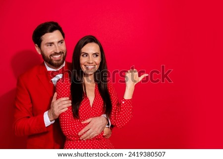 Photo portrait of attractive young couple point empty space valentine day dressed stylish elegant clothes isolated on red color background