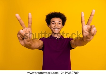 Photo of funky cheerful man wear stylish burgundy clothes two arm shows v-sign symbol isolated on yellow color background