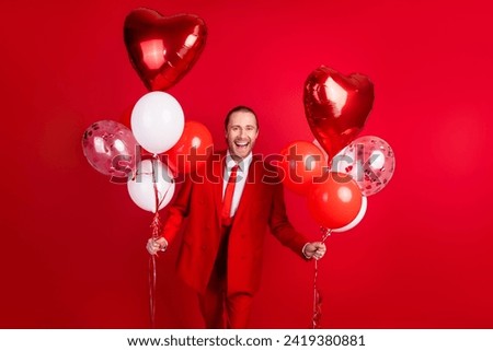 Photo portrait of attractive young man hold excited air balloons wear trendy classic clothes isolated on red color background