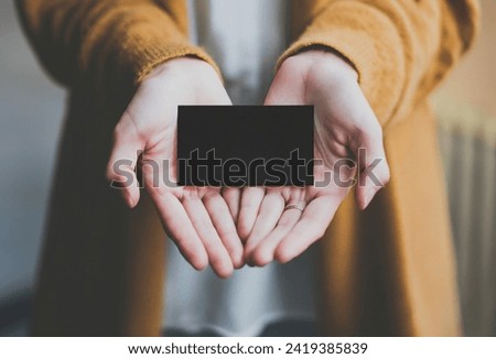 mockup of a woman holding and showing a black business card with empty space