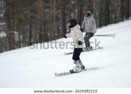 Ski slope in a pine forest. A man teaches his child to ski. Copy space.                               