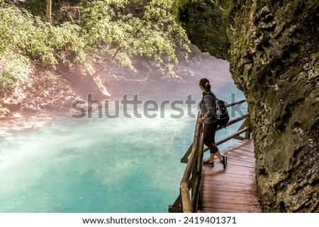 Woman looking into the water on the wooden path in the Vintgar Gorge in Slovenia. Royalty-Free Stock Photo #2419401371
