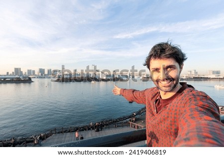 people, travel, tourism, friendship and technology concept - happy tourist taking selfie with smartphone  at bridge at tokyo in japan background