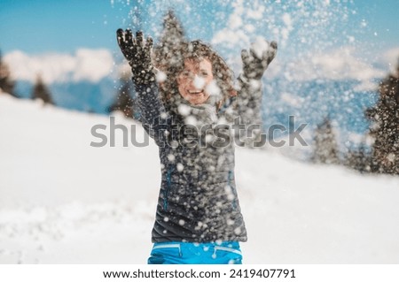 Whirling Winter Wonder: A Spirited Young Girl Launches Snowflakes Into the Sky! Royalty-Free Stock Photo #2419407791