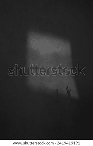 black and white photo of a shadow of the hands in the wall. hand silhouette looks like ghost out the window. Defocus palm of hand shadows on rough wall surface. Help. 