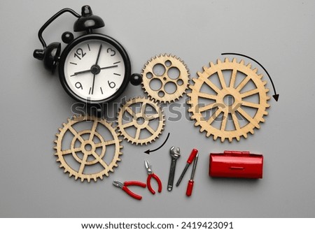 Flatlay picture of wooden gear with alarm clock and repairing tools. Technical and mechanical concept