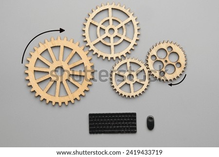 Flatlay picture of wooden gear with miniature keyboard and mouse. Technical support.