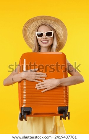 Close up vertical photo of young woman over isolated yellow background in vacation with travel suitcase. Caucasian female traveler explorer ready to go on voyage trip holiday Royalty-Free Stock Photo #2419437781