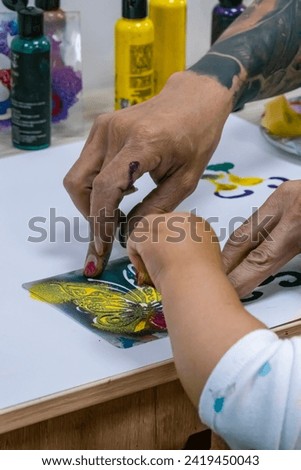 Paint handling art class for children, man and boy hands, classroom, child learning, artistic expression, vertical photo