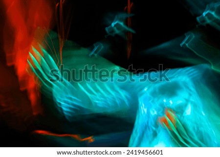 A blue birds wings flapping in the night, red and turquoise isolated on black.