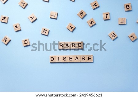 Words Rare Disease composed of wooden blocks with letters on blue background. Healthcare concept. Selective focus, copy space Royalty-Free Stock Photo #2419456621