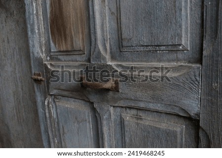 An old curly wood door and an iron handle has become black in colour.