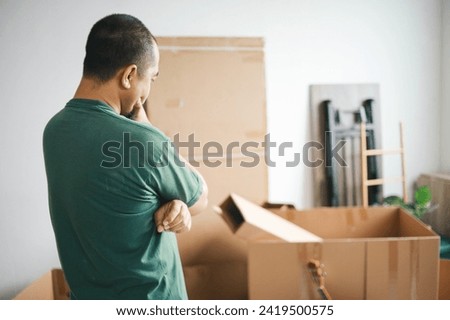 Man standing by cardboard boxes at home, preparation for moving out.