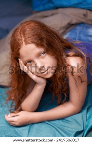 Thinking, camping and child in sleeping bag for resting, relaxing and comfortable in tent. Travel gear, daydreaming and young girl in sleep sack for adventure on holiday, vacation or weekend outdoors Royalty-Free Stock Photo #2419506017