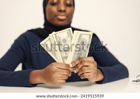 Arabic entrepreneur sitting in her office and holding cash