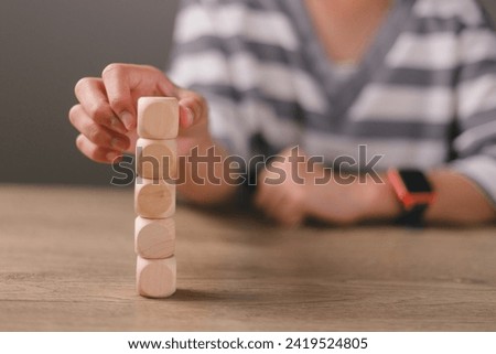 Businesswomen stack blank wooden cubes on the table with copy space, empty wooden cubes for input wording, and an infographic icon