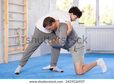 Father teaching his son wrestling or self-defense techniques in the gym