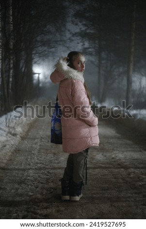 A girl poses against the backdrop of heavy fog on the street.