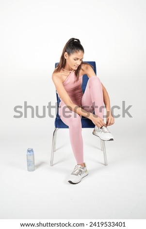 Talented young woman sitting on blue chair tying shoe lace