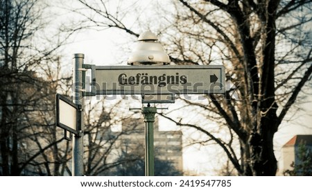 The picture shows a signpost and a sign that points in the direction of the prison in German.