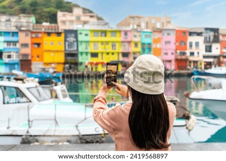 Young female traveler taking a photo of colorful Zhengbin Fishing Port landmark and popular attractions in Taiwan