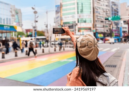 Young female tourist taking a photo of the Rainbow Road crossing at ximending in Taipei, Taiwan