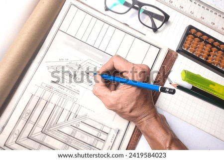 hand making technical drawings of roof trusses using wood