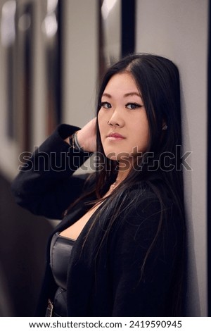 Portrait of a beautiful young Asian woman in a black coat and boots