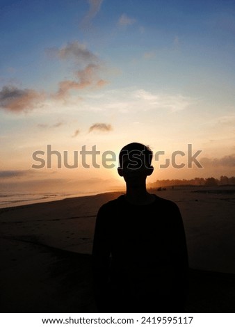 Jawa Barat, Indonesia 31 January 2024- A picture of man standing upright with his back facing the sun, concept of nature and beauty. Orange sunset, human silhouette