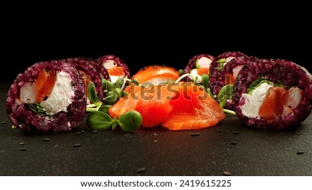 Variety of bright sushi rolls with greens on a black background. Incredible fresh sushi rolls on a dark background. Cooking traditional Japanese seafood and fish dishes.