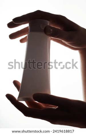 Close-up of a white mockup of a tube of cream in female hands on a white background.