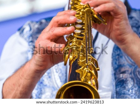 close-up of the hands of a musician playing the soprano saxophone