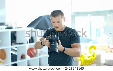 Male photographer holding black professional camera in his hands in studio. Hobbies doing what you love concept