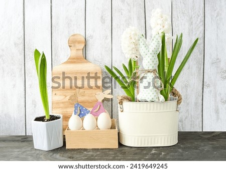 Decorative Easter composition on a wooden background, spring flowers hyacinths and cute wooden bunnies in a box with Easter eggs.  Foreground.  Easter holiday concept, holiday decor.