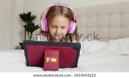 Emotion excited surprise child in headphones playing digital tablet computer home. Application for children development. Toddler watch interesting learning video, movie, online class, listen to music