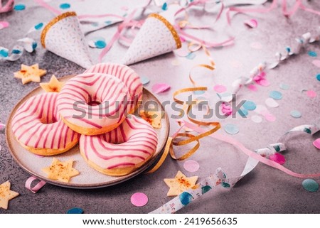 Donuts for carnival and party. German Krapfen or donuts with streamers and confetti. Colorful carnival or birthday image