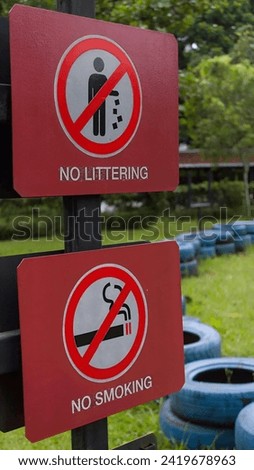 A no-littering and no-smoking sign in a park surrounded by decorative car tires.