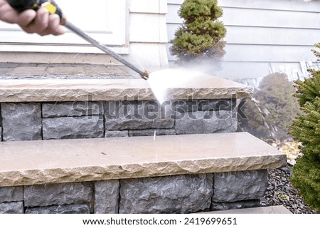 Close up of high pressure water jet during cleaning dirty outdoor porch stairs.