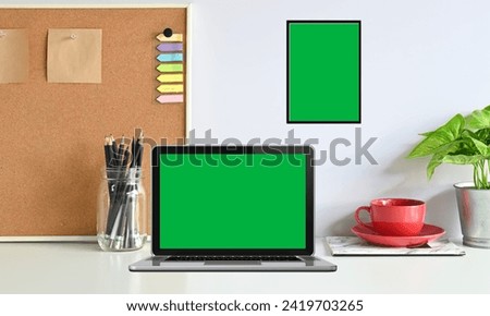  Laptop Computer Showing Green Screen Stands on a Desk in the open environment. In the Background Living Room in the Evening with Warm Lights on.