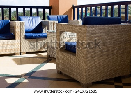 Wicker chairs with armrests and soft cushions for outdoor seating on the terrace on a sunny day
