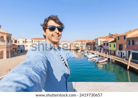 Happy traveler man taking a selfie on famous Murano island near Venice. Travel and vacation concept in Italy