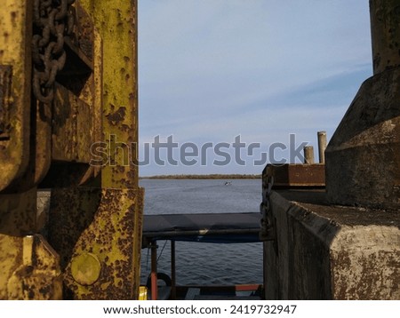 Amazing photo abstract cloudy blue sky, beautiful waters, passing fishing boats, seen from behind an old rusty steel bridge pillar. Majingklak Pier, Pangandaran, West Java. Royalty-Free Stock Photo #2419732947